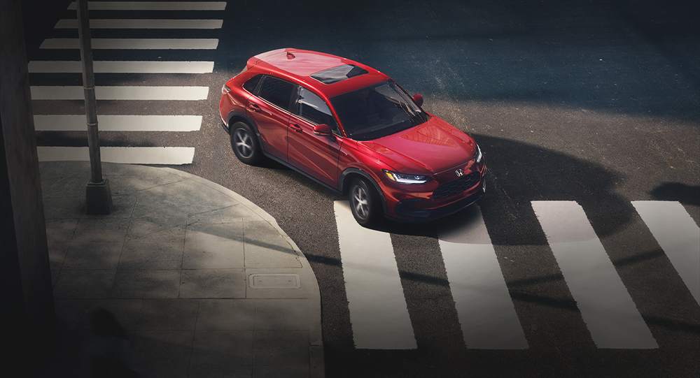 Overhead view of the 2025 Honda HR-V EX-L in Milano Red, shown navigating a city intersection.